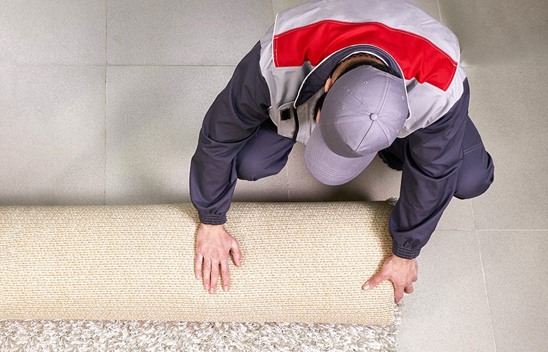 male-worker-unrolling-carpet-floor-home-view-from